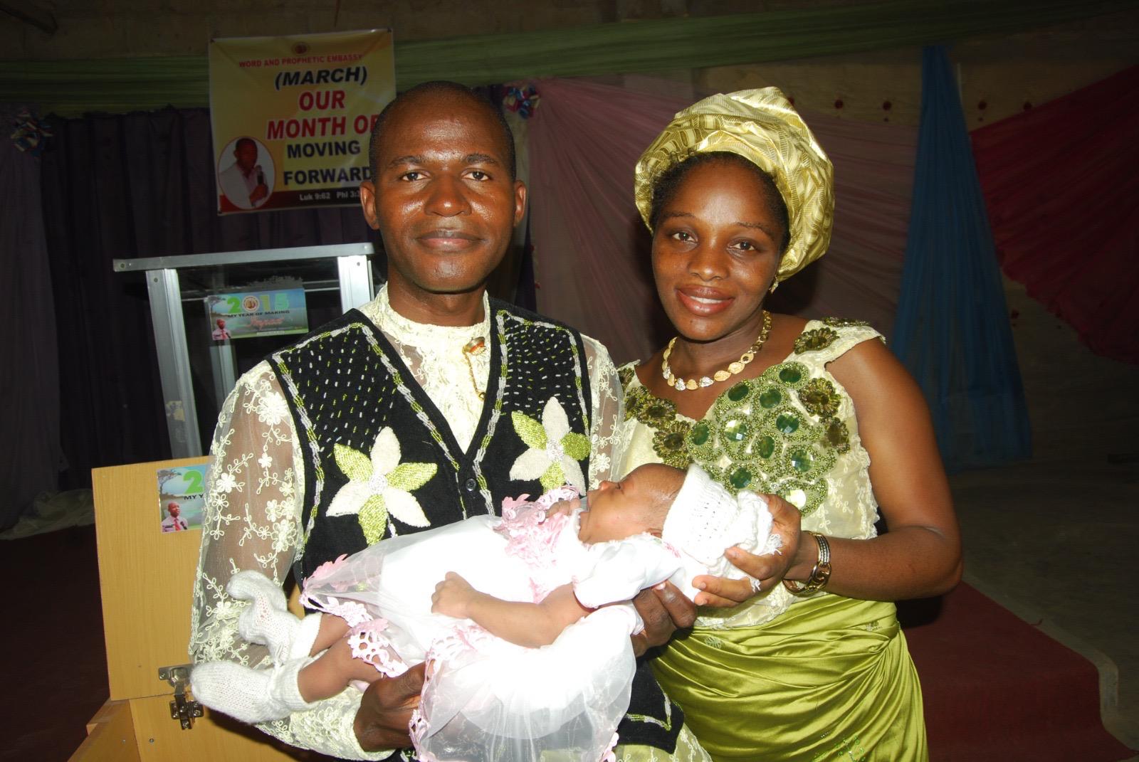 Abimbola and his wife holding their newborn at church
